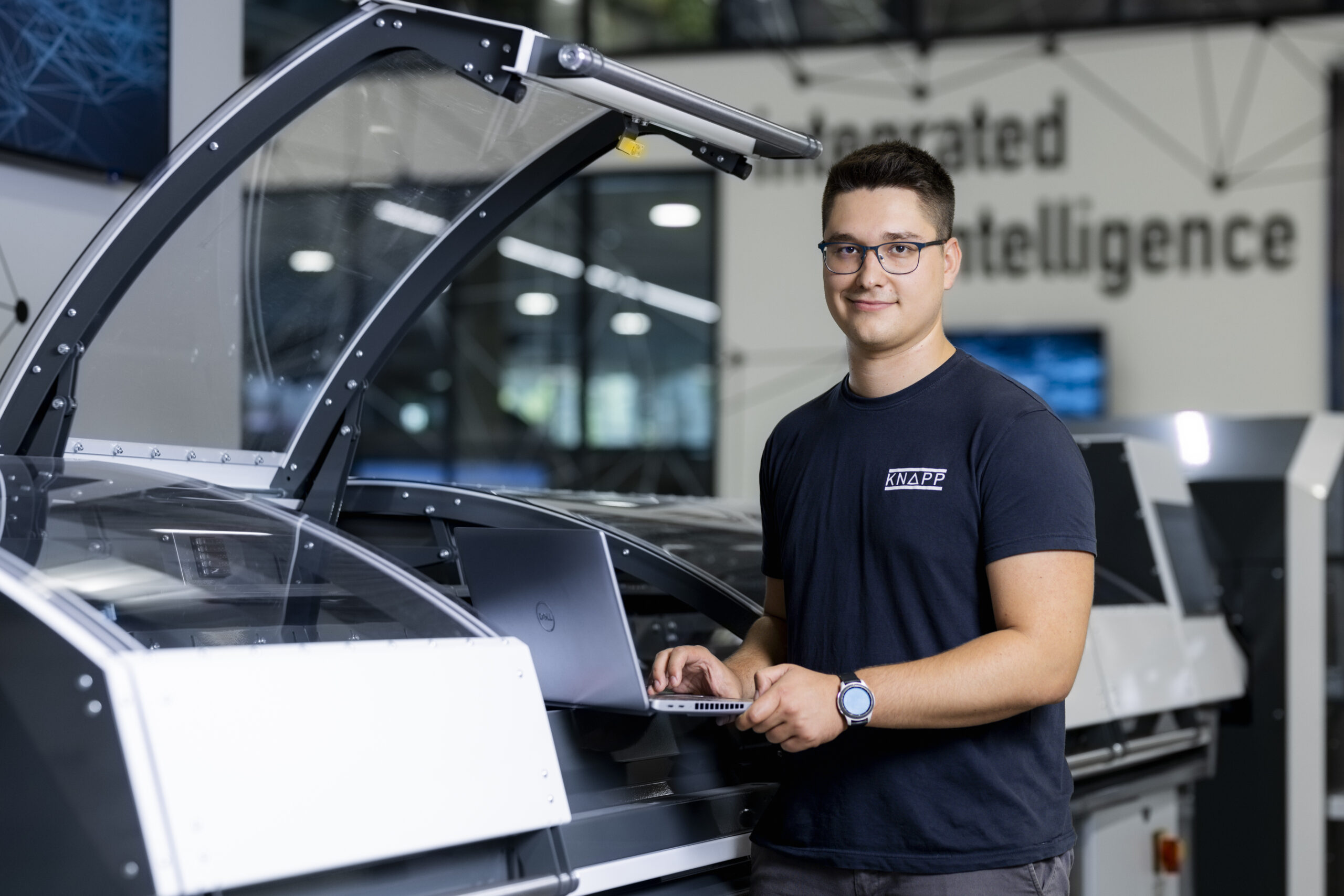 Ein Mann mit Brille und dunklem T-Shirt arbeitet an einem Laptop und überwacht die Inbetriebnahme von Software.
