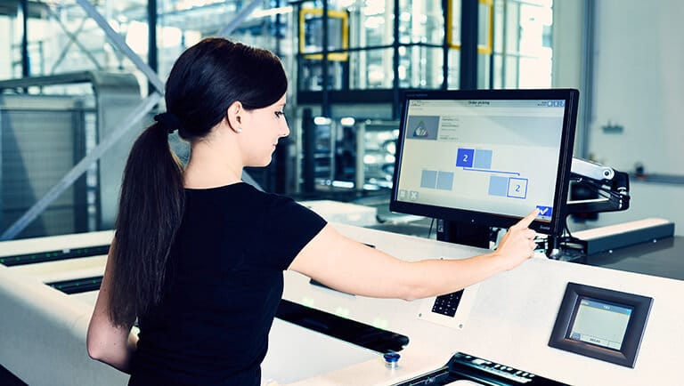 Employee at the Pick-it-Easy work station operating an easyUse user interface on a touch screen. The easyUse interfaces increase usability and the user experience in the warehouse for warehouse workers