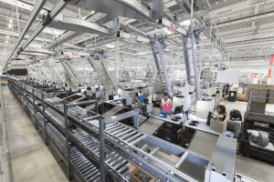 The image shows a hall with loading stations and packing stations in the Decathlon distribution center. Employees work at these work stations in a modern work environment.