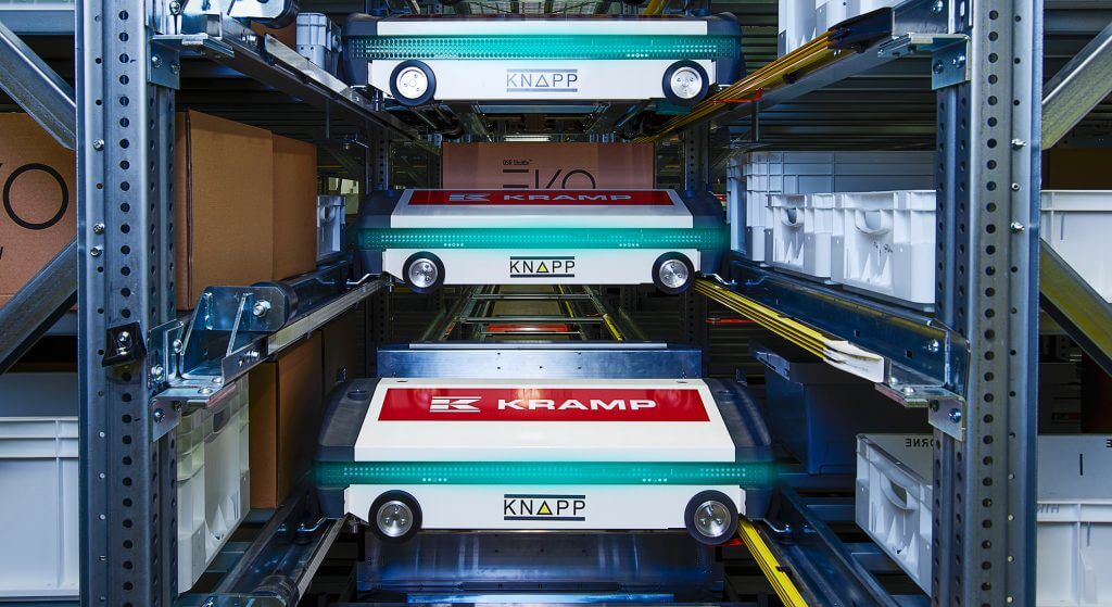 Vista de un pasillo del sistema de almacenamiento automático OSR Shuttle™ Evo en KRAMP. Se ven desde delante dos lanzaderas y una tira de LED indica el estado de las lanzaderas. El mantenimiento del sistema de almacenamiento automático OSR Shuttle™ Evo es sumamente fácil.