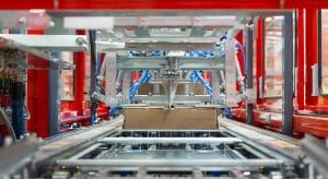 Automated packaging machinery producing right-size cartons in a logistics facility