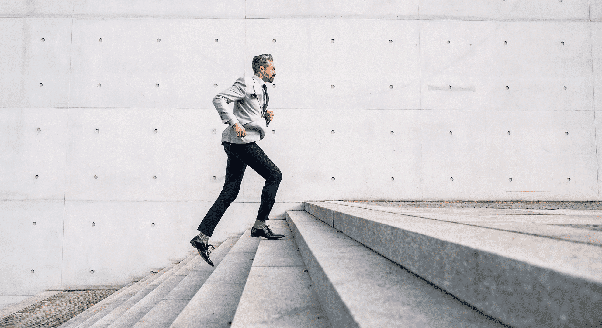 Un homme vêtu d’un costume moderne et tendance monte un escalier en courant