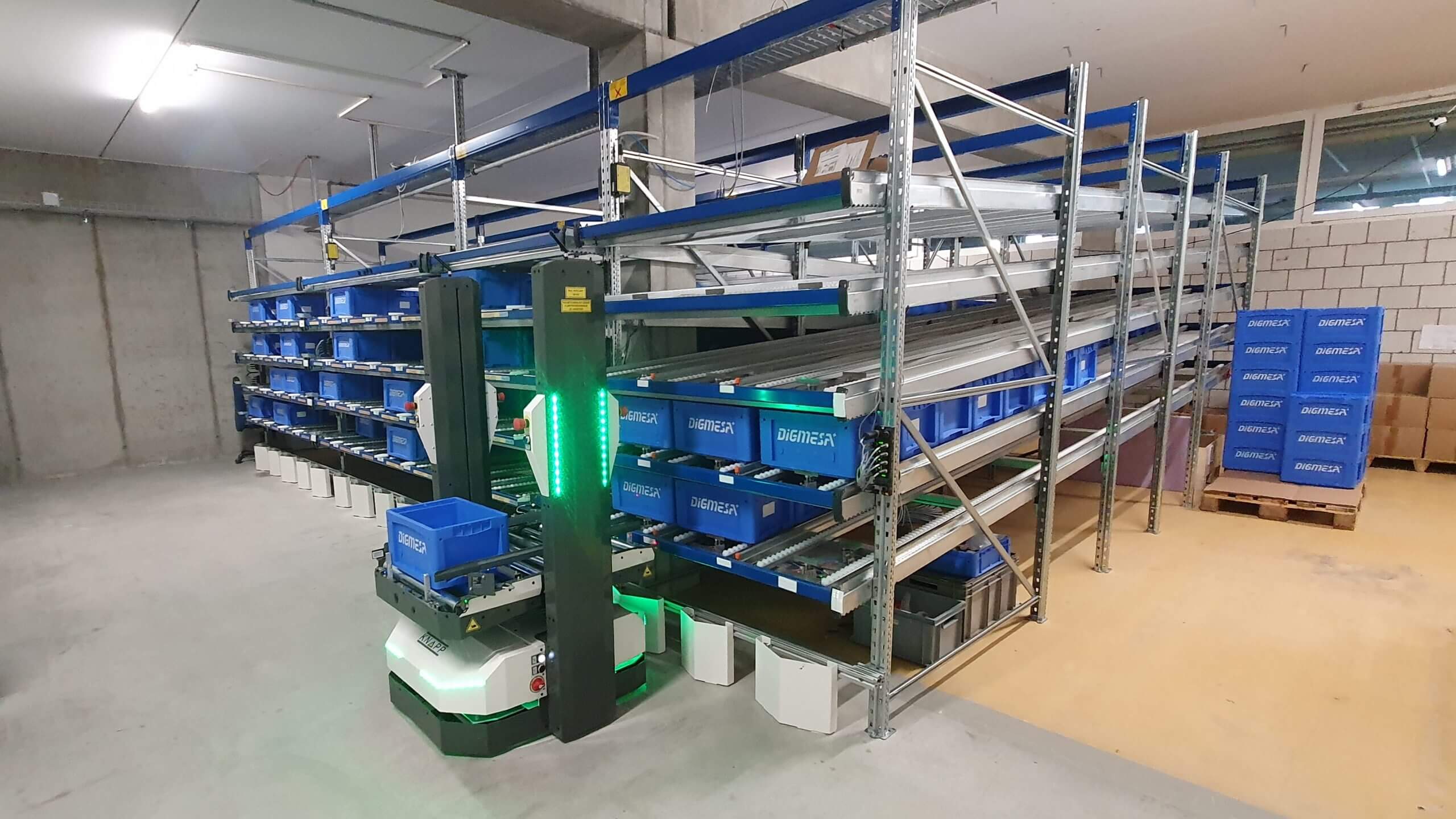 The autonomous intelligent vehicle (AIV) from KNAPP, called Open Shuttle, hands off containers to a flow rack.