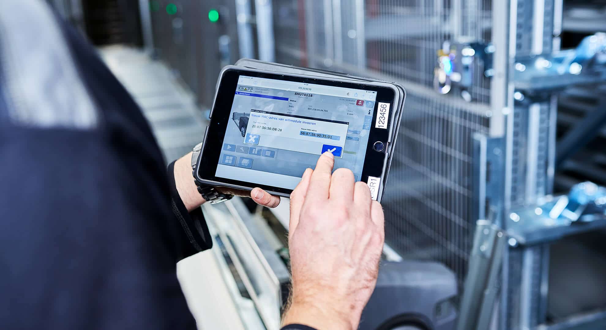 Eine Person bedient im Logistikzentrum von KRAMP ein Tablet mit KiSoft SCADA.