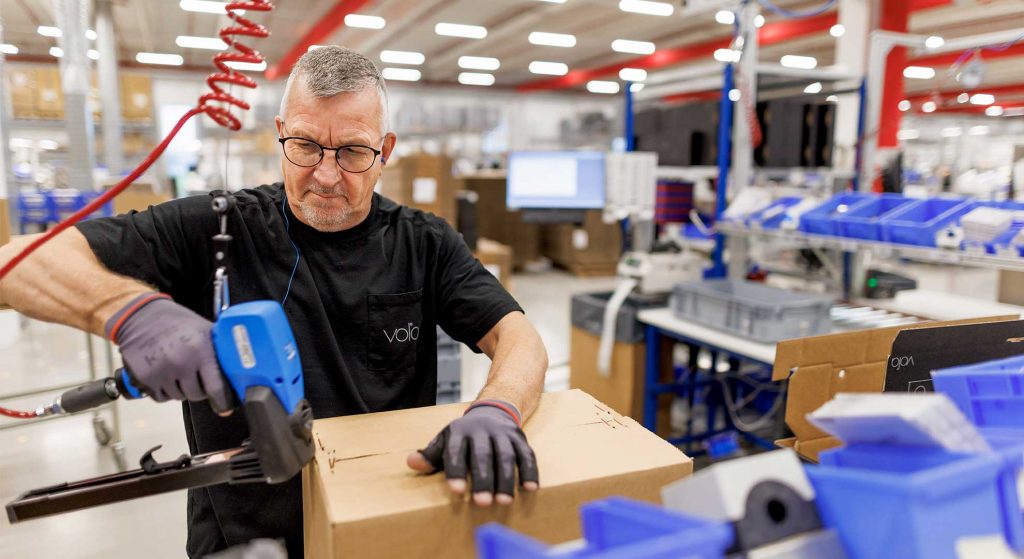 Un employé ferme un carton dans la halle de production.