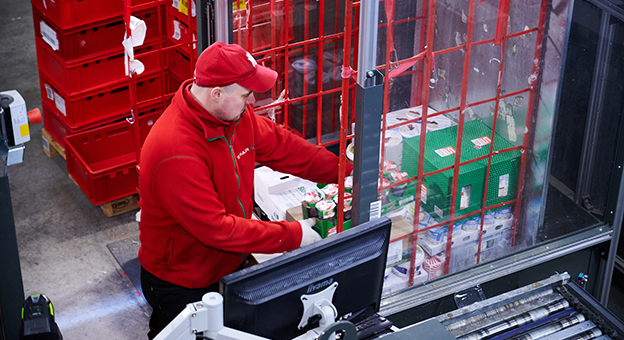 A warehouse worker is working at the ergonomically designed work stations that are part of the solution for store delivery at SPAR.