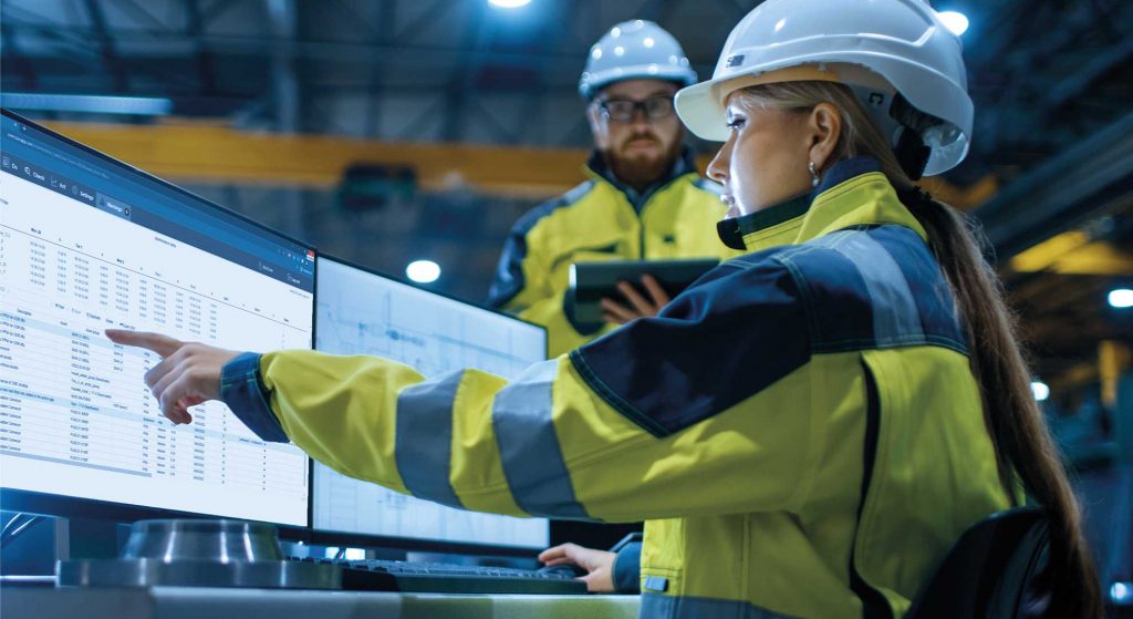 Le concepteur et le technicien discutent d’un sujet, le concepteur montre du doigt un écran sur lequel sont affichées différentes données