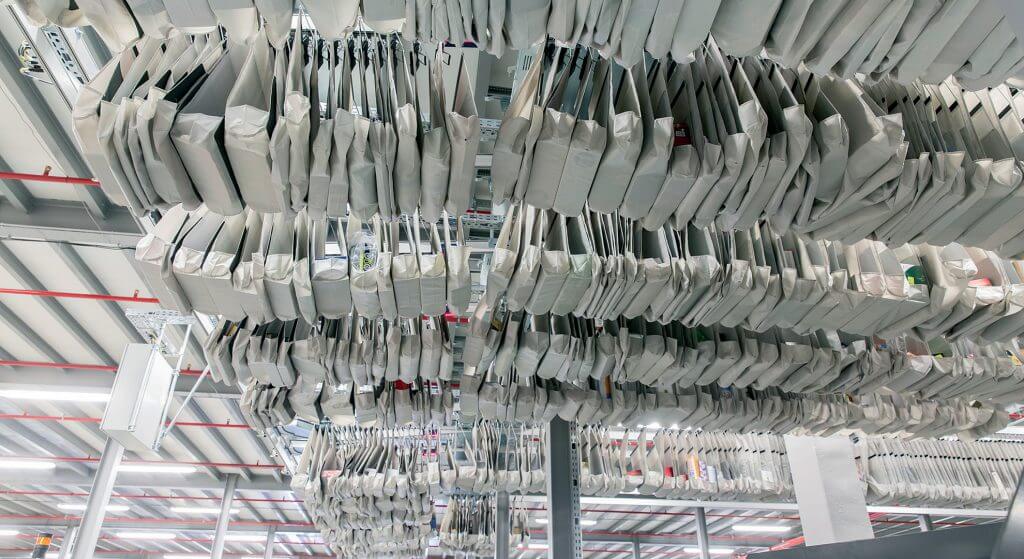 View from below of a Dürkopp pocket sorter system conveyor system for sorting and hanging and flat-packed goods at the Czech online retailer mall.cz. Many sorter pockets can be seen from below. The sorter pockets are conveyed with the aid of a pocket sorter system. One item of goods is transported in each sorter pocket. Each sorter pocket in the pocket sorter system is equipped with an RFID transponder. Thus each sorter pocket in the pocket sorter system can be easily retrieved.