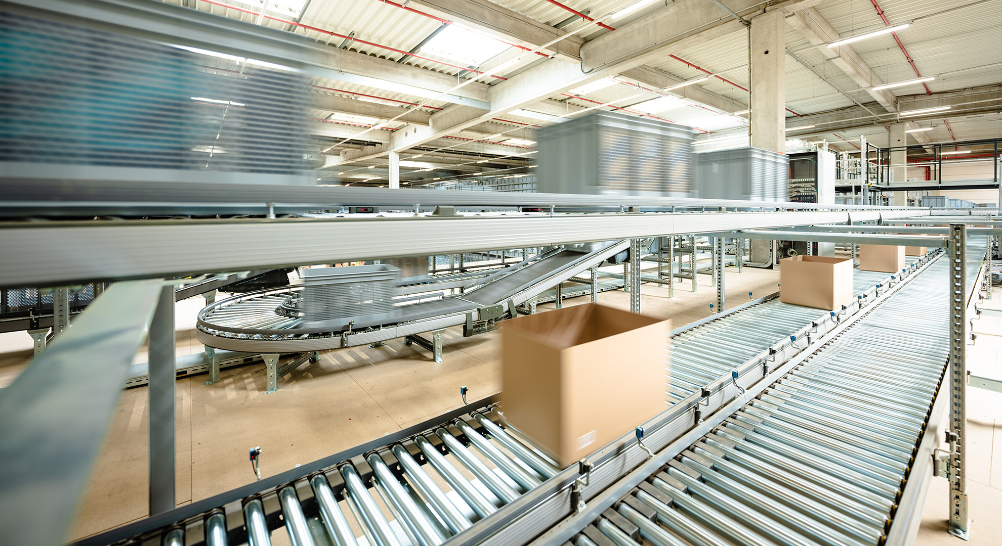 Several packages travel on a conveyor belt in a warehouse.