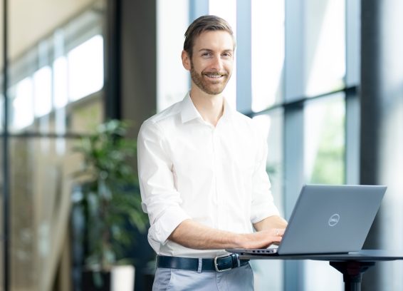 Andreas Krassnig KAG 004 Ein Kollege steht an einem Stehtisch und arbeitet an seinem Laptop