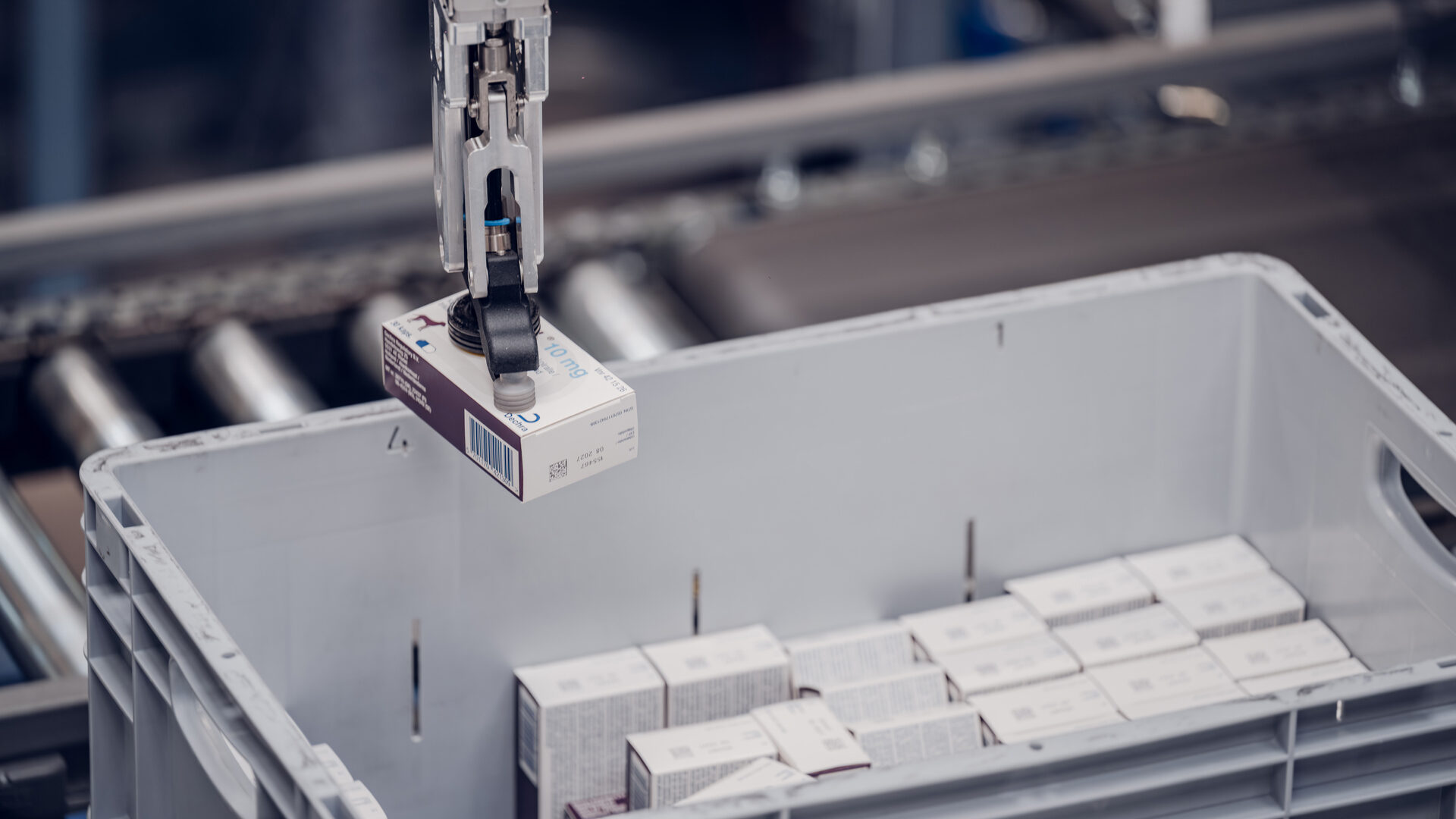 Apotek-1-oslo-box Ein Roboterarm legt eine Schachtel in eine graue Tonne auf einer automatisierten Linie - Victorinox setzt auf zentrale Distribution für Effizienz.