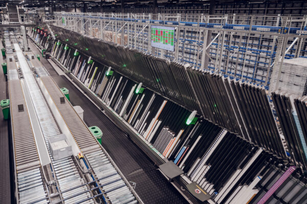 Apotek-1-sda Automatisches Förder- und Sortiersystem in einem großen Lager - Victorinox setzt auf zentrale Distribution mit grünen Lichtern, die die Pakete zu ihren Plätzen führen.