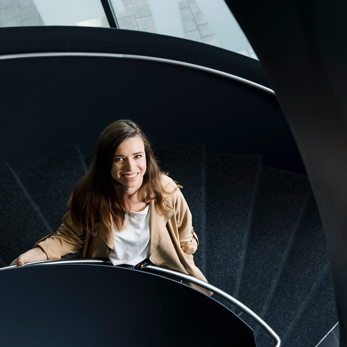 Christina Kritz steht auf einer tieferliegenden Treppenstufe und lächelt nach oben in die Kamera