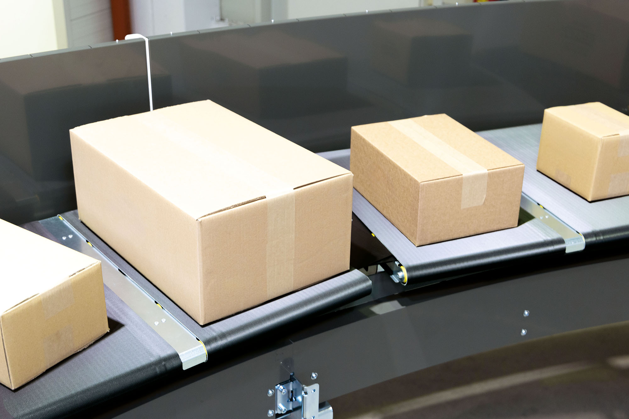 Cross Belt Sorter In einem Lager oder Distributionszentrum laufen mehrere Kartons über ein Förderband, das von intelligenten Sortiersystemen gesteuert wird, um den Versand und die Sortierung zu rationalisieren.