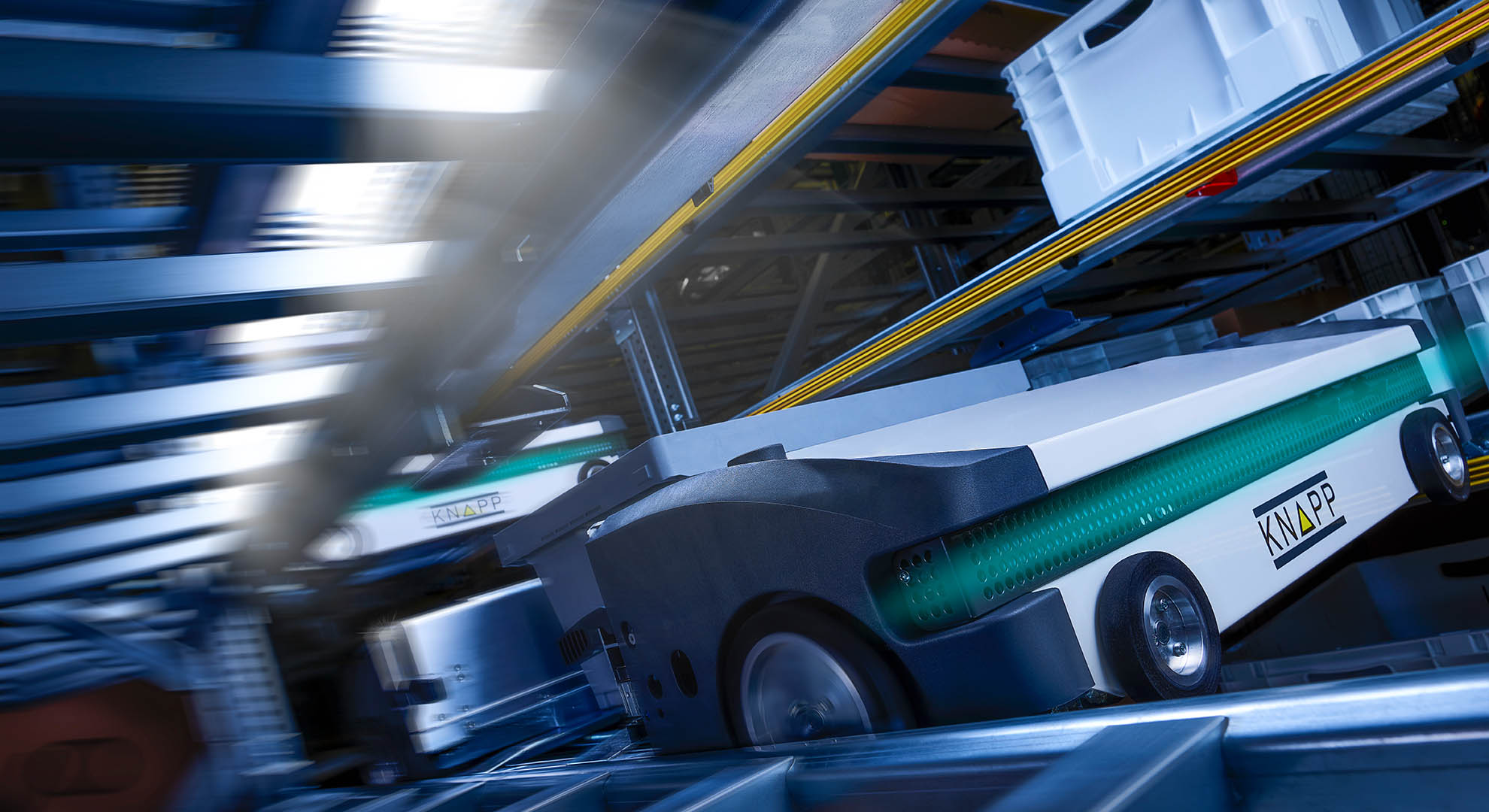 Closeup of a shuttle robot, conveying a container through an OSR aisle.