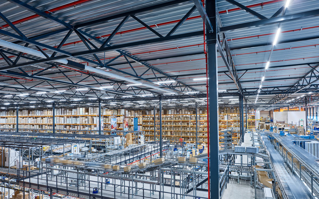 Centre de distribution de Mediq à Bleiswijk Vue d’ensemble d’un entrepôt automatisé avec des rayonnages en hauteur et des systèmes de convoyage.