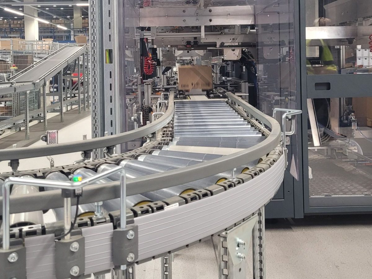 Driv_willebroek_iPack_es En el sistema de transporte de la estación de embalaje de DRiV se desplaza una caja de cartón a través del sistema de transporte.