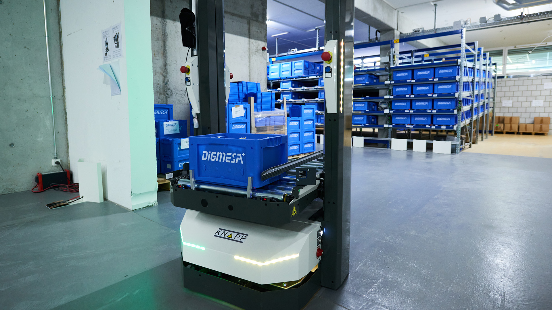 Un robot AMR de Digmesa transporta cajas DigiMex azules por un almacén