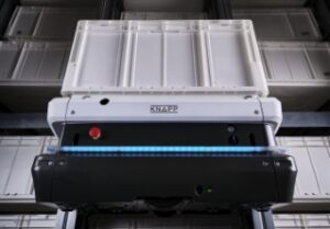 Nahaufnahme eines weißen Industrieroboters oder einer automatisierten Lagereinheit von KNAPP mit blauem Licht und Steuertasten in einem Lager.