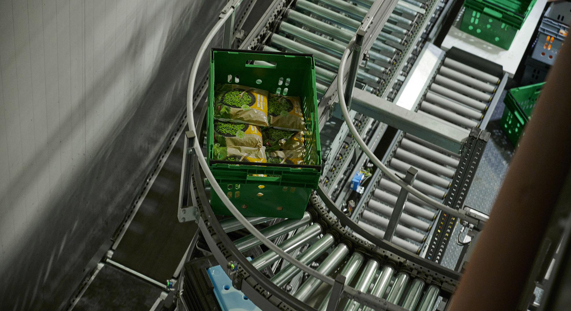 Frozen foods and cold packs in a container on a conveyor belt in a freezer warehouse.