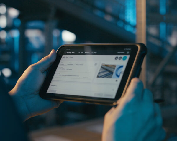 ICS_One_step_ahead_zukunftsweisende_Technologien_ Ein Wartungstechniker hält ein Tablet in der Hand mit einem Task unseres digitalen Wartungsmanagementtools, KiSoft CMMS.