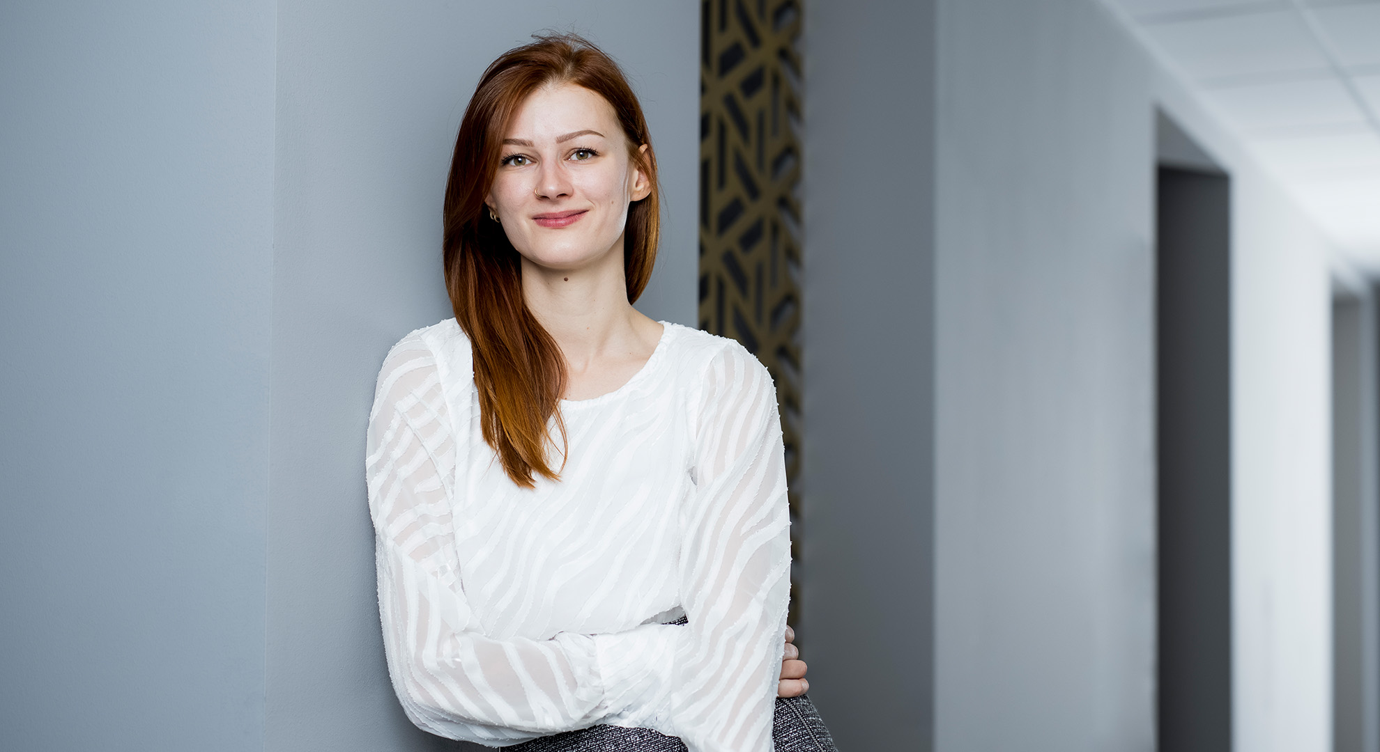 KNAPP-Spirit: Innovatoren Jana-Alena Hochsteger lächelt an eine Wand gelehnt freundlich in die Kamera