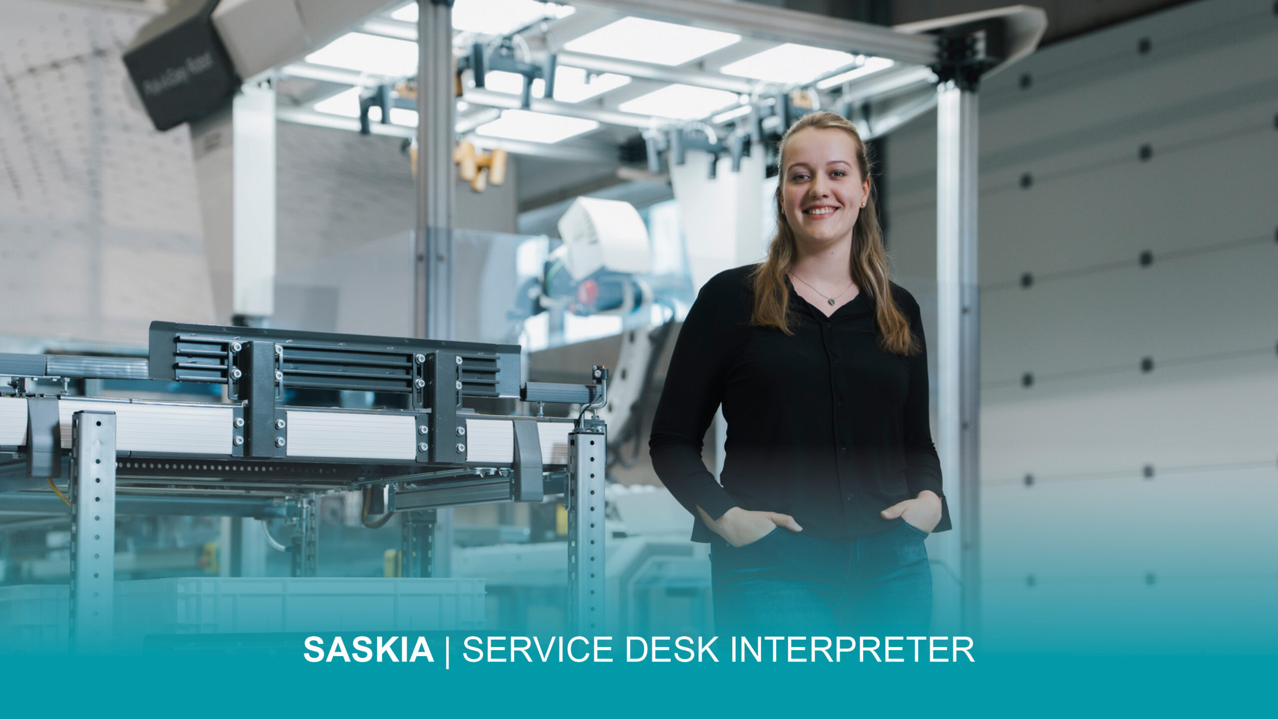 Karrierewege_Saskia_Service Desk Interpreter Femme debout, souriante, dans un environnement de stockage moderne, la main dans la poche ; le texte suivant est intégré à l'image : « SASKIA | SERVICE DESK INTERPRETER ».