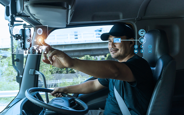 Ein Lkw-Fahrer interagiert mit einem futuristischen Touchscreen-Display von KiSoft Driver, das vor ihm projiziert wird und digitale Schnittstellengrafiken zeigt.