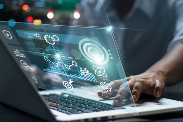 KiSoft_wms_hero Eine Person, die einen Laptop mit digitalen Datenvisualisierungen und KiSoft WMS-Symbolen über der Tastatur benutzt, symbolisiert futuristische Datenverarbeitung und Analytik.