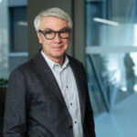 A technology provider with grey hair and glasses, wearing a button-down shirt and blazer.