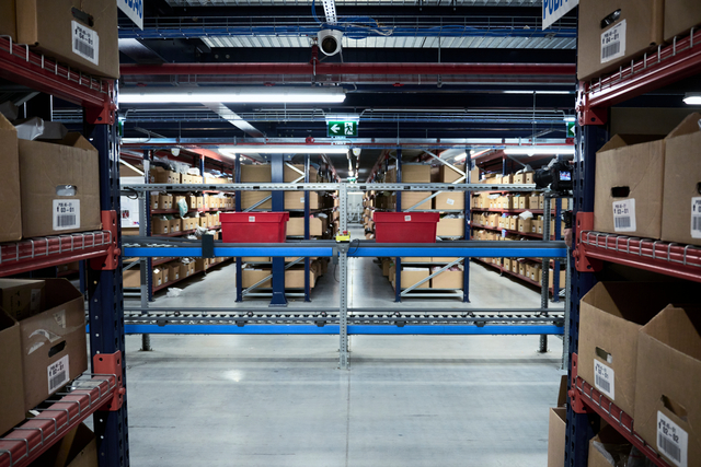 Zwei Behälter fahren auf einer abziehenden Fördertechnik im manuellen Lagerbereich von eMAG.