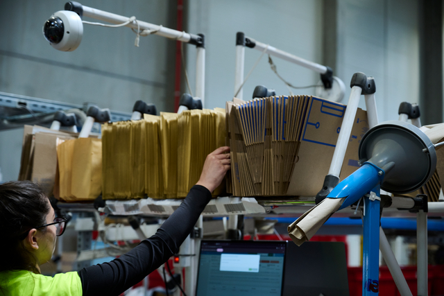 Eine Frau greift nach einem Versandkarton an eMAGs Packstationen.