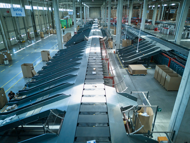 Die Versandware wird bei eMAG im Lager über den Cross-Belt-Sorter sortiert und über Rutschen in Versandbehälter übergeben.