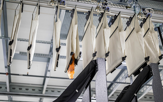 Hängende Taschen eines automatisierten Sortiersystems bewegen sich entlang einer Förderstrecke zur Sortierung und Verteilung von in Polybag verpackten Artikeln.
