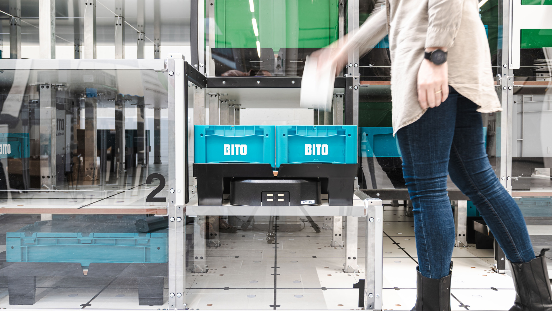 Une personne place un article dans un bac de stockage BITO bleu sur une étagère métallique dans un entrepôt moderne d'automatisation d'entrepôt Industrie.