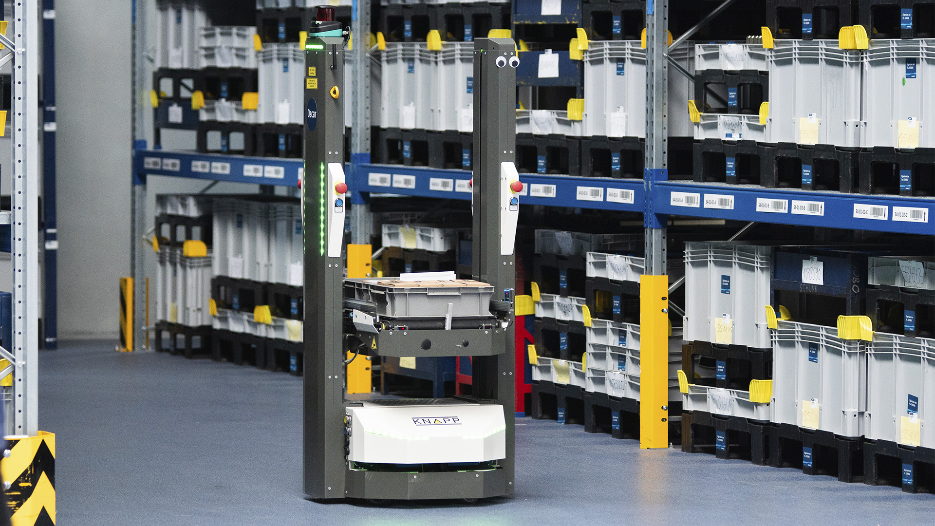 Mobile robot deployed at Schunk An autonomous mobile robot runs through a manual warehouse area carrying a gray container.
