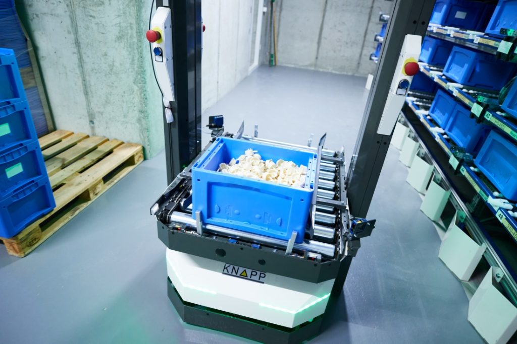 Open Shuttle Spritzgussteile Digmesa Logo entfernt web An autonomous mobile robot transports a blue container filled with injection-molded parts.