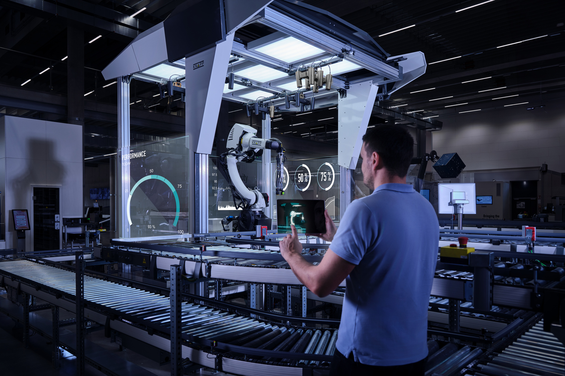 Plattformen_hero Ein Mann steht vor einer automatisierten Hightech-Maschine mit Roboterarmen und digitalen Anzeigen in einer modernen Fabrik und verwendet in der Nähe von Förderbändern eine Supply-Chain-Software auf seinem Tablet-Gerät.