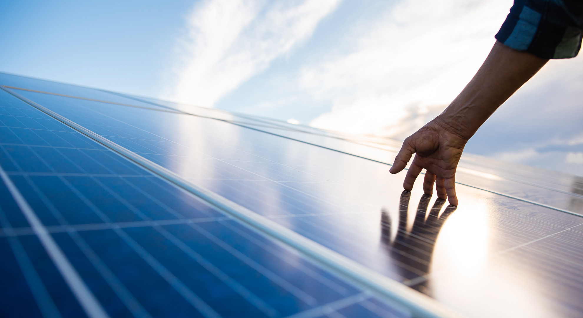 A hand touches a solar panel that generates energy