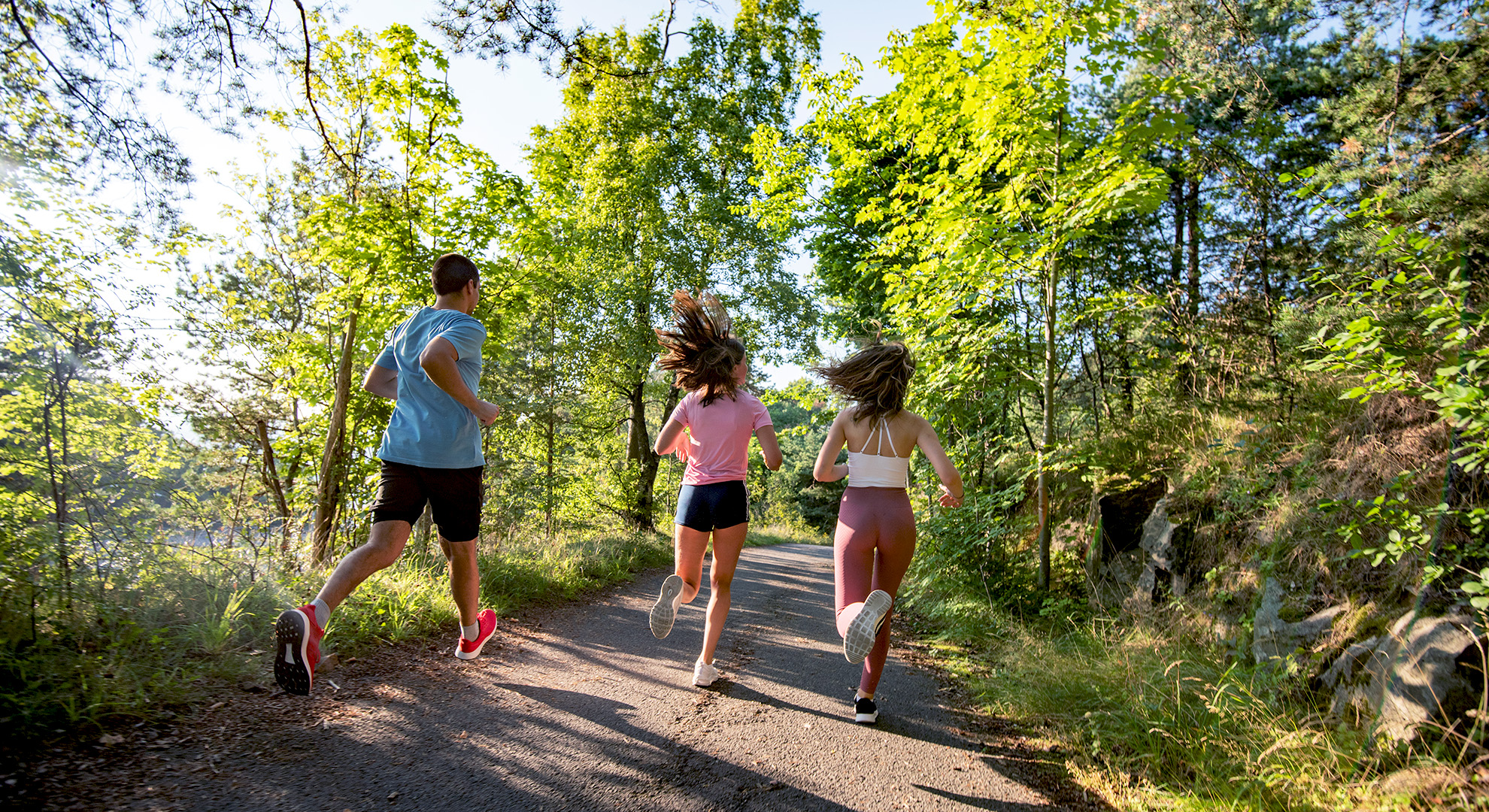 A small group of people run through a forest