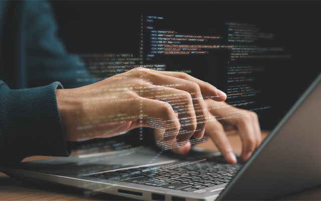 Eine Person tippt auf einer Laptoptastatur, wobei im Vordergrund Zeilen von Computercode digital eingeblendet sind, was auf Programmierung oder Softwareentwicklung für Lieferkettensoftware hindeutet.