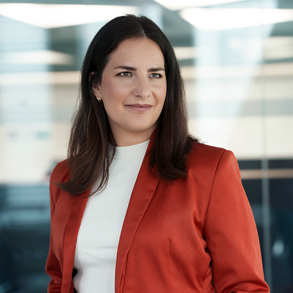 Sales Manager Verena im Business-Look mit rotem Blazer
