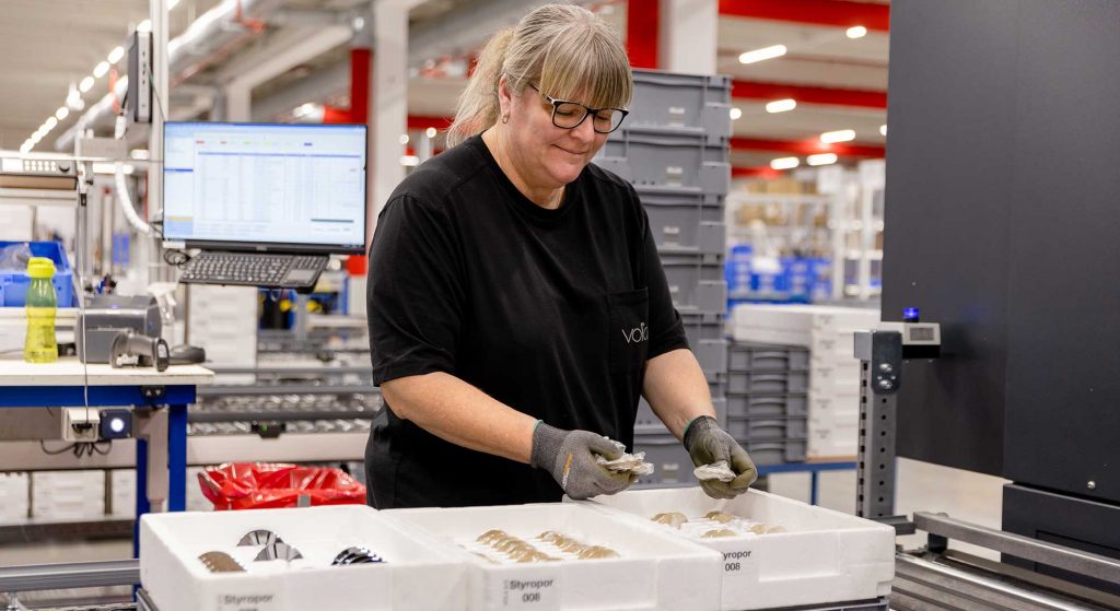 Female worker standing in production hall packing VOLA goods for shipping