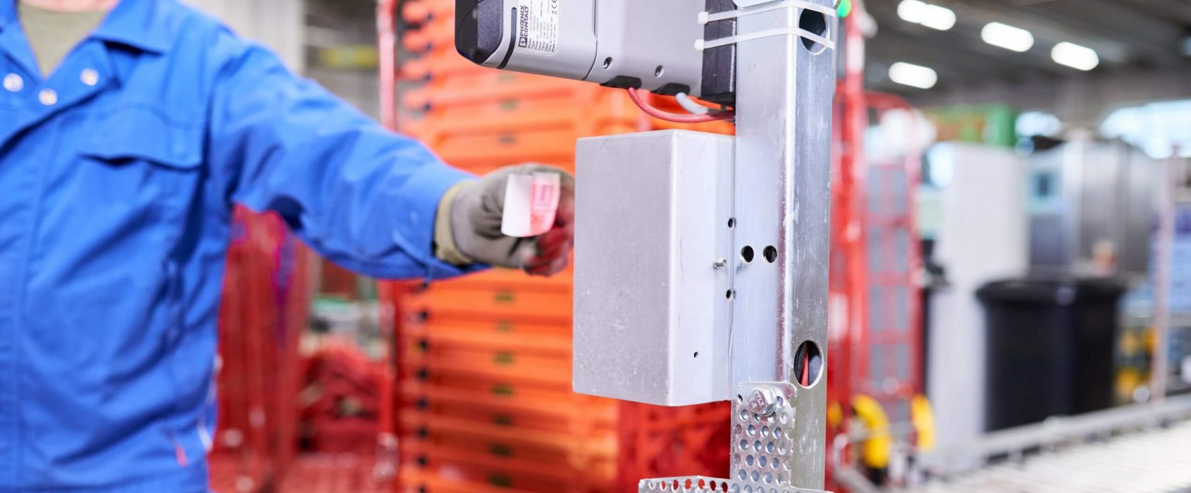 Close-up picture of a Cleanaway employee scanning a ticket at a terminal for booking according to store. This is how empties receiving starts. There are unsorted empties in the background that will soon be placed on the conveyor system.